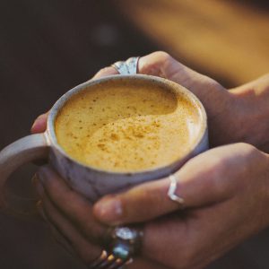 Nutra Organics Golden Latte in a cup being held with two hands