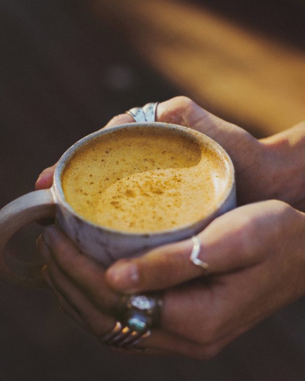 Nutra Organics Golden Latte in a cup being held with two hands