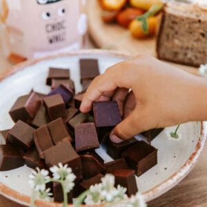 Nutra Organics Choc Whiz gummies on a plate with child picking one up
