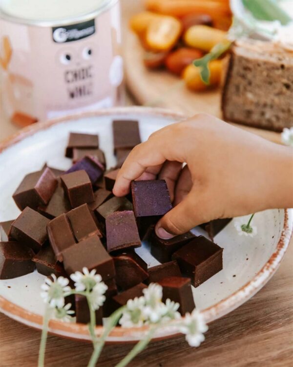 Nutra Organics Choc Whiz gummies on a plate with child picking one up