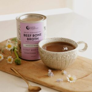 A stylized image of A Nutra Organics Beef Broth in Mushroom flavour container next to a cup of hot beef broth
