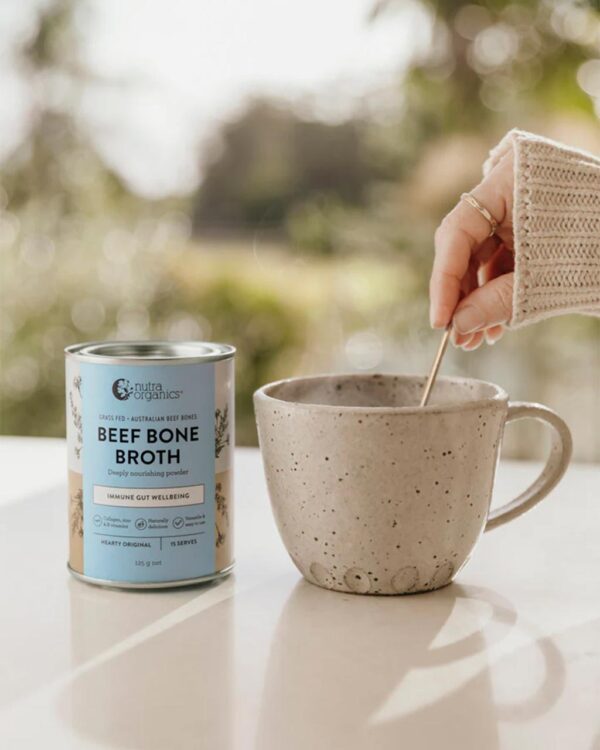 A stylized image of cup of hot Nutra Organics Beef Bone Broth alongside a 125g container of the product
